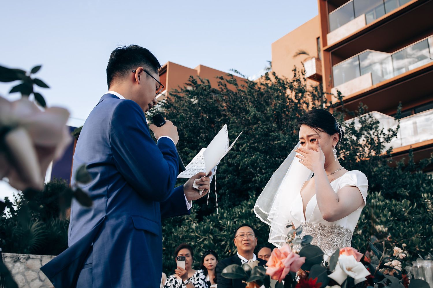 Outdoor wedding ceremony with couple exchanging vows in garden setting.