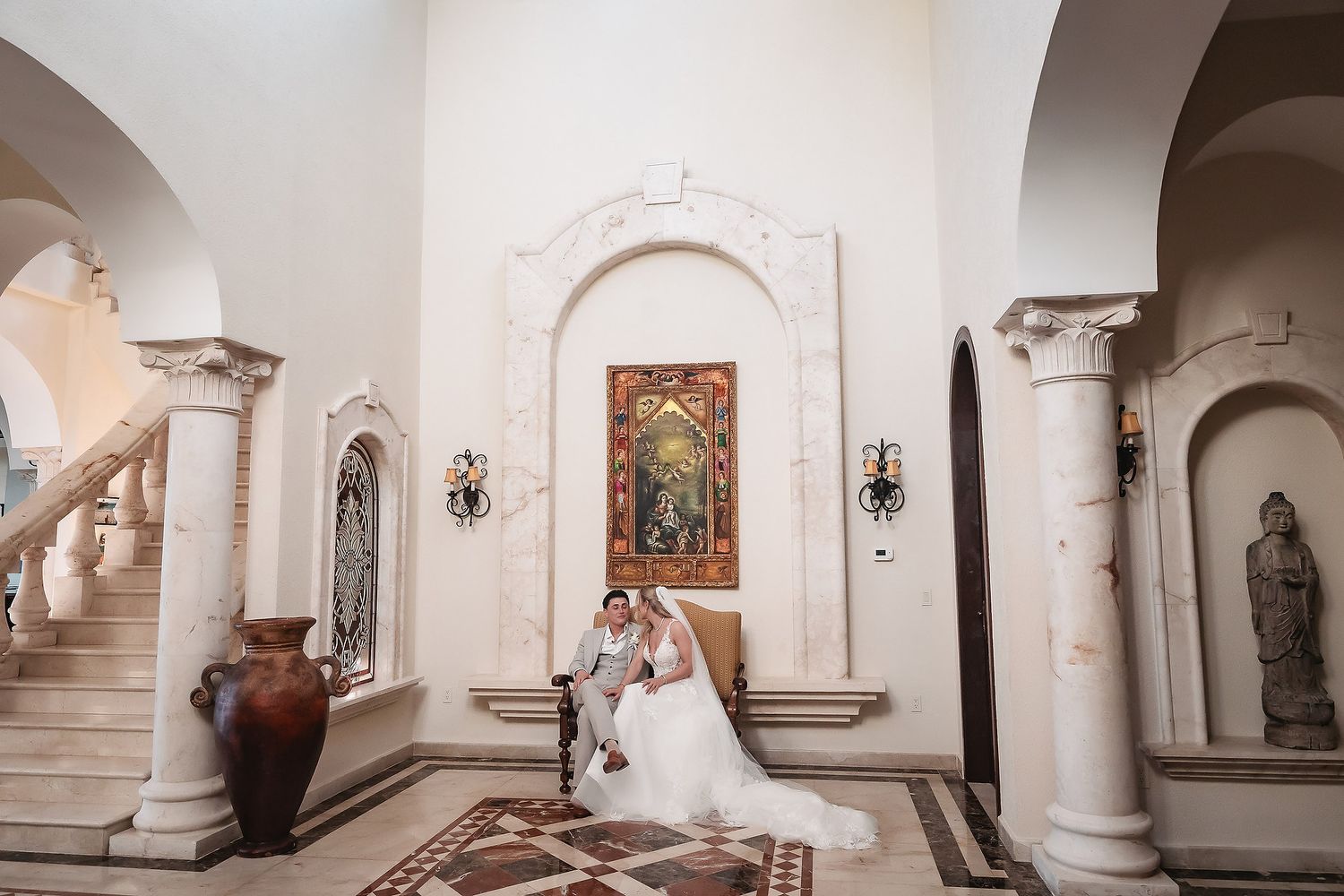 Interior of Spanish colonial church with white columns and arched walkways during wedding celebration.