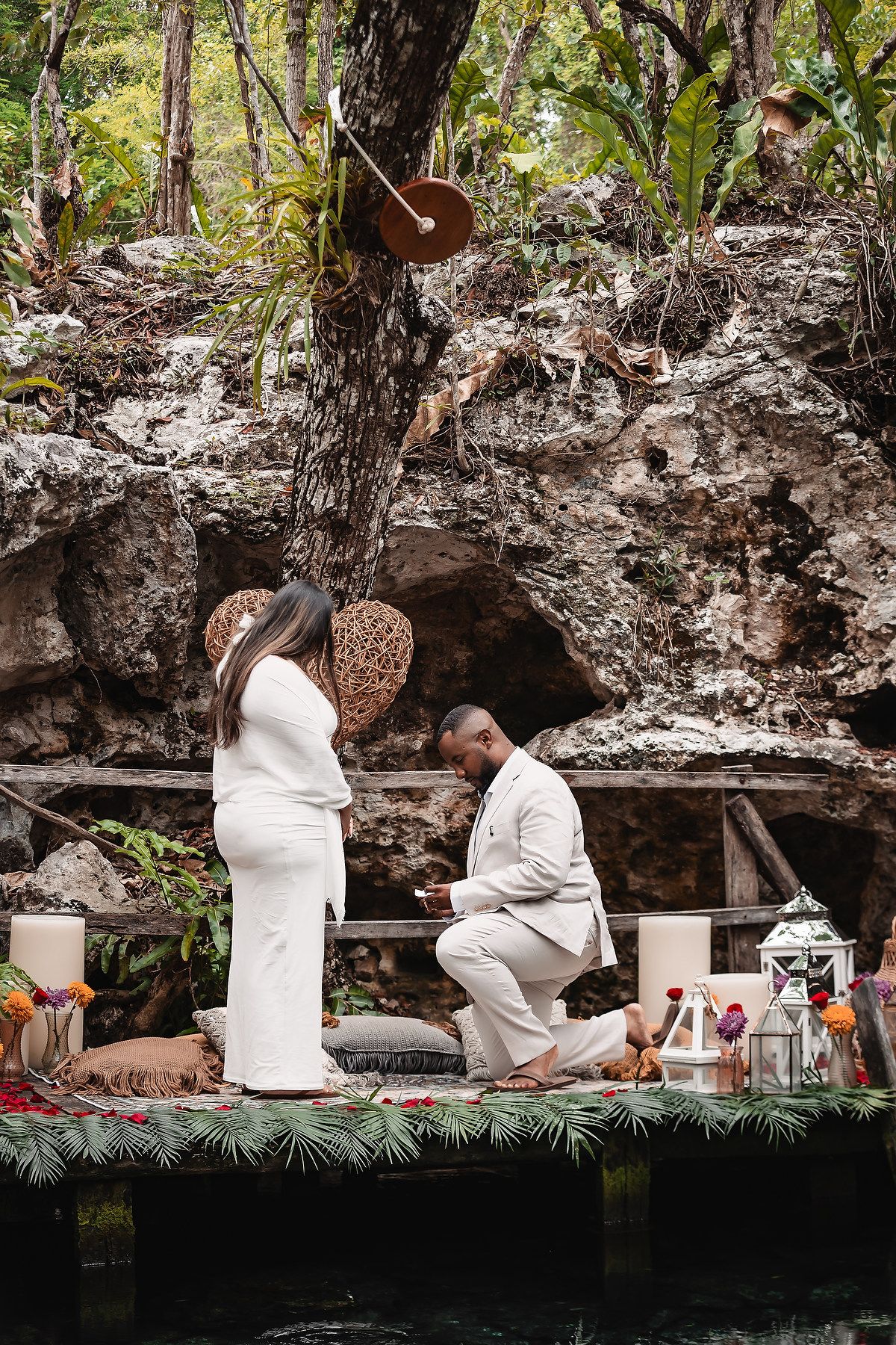 Proposal scene with white-clad figures on decorated platform by natural cave pool.