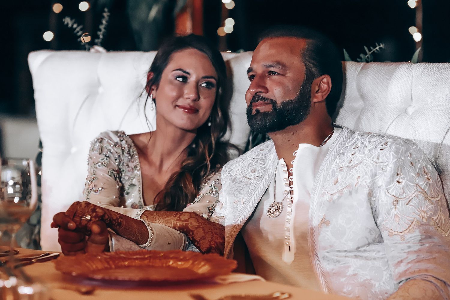 Couple in wedding attire sharing an intimate moment while holding a wine bottle during their celebration.