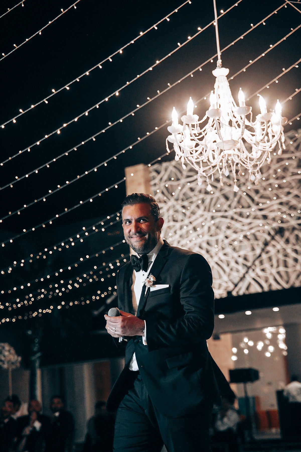 Elegant reception venue with twinkling string lights and ornate chandeliers creating a magical atmosphere.