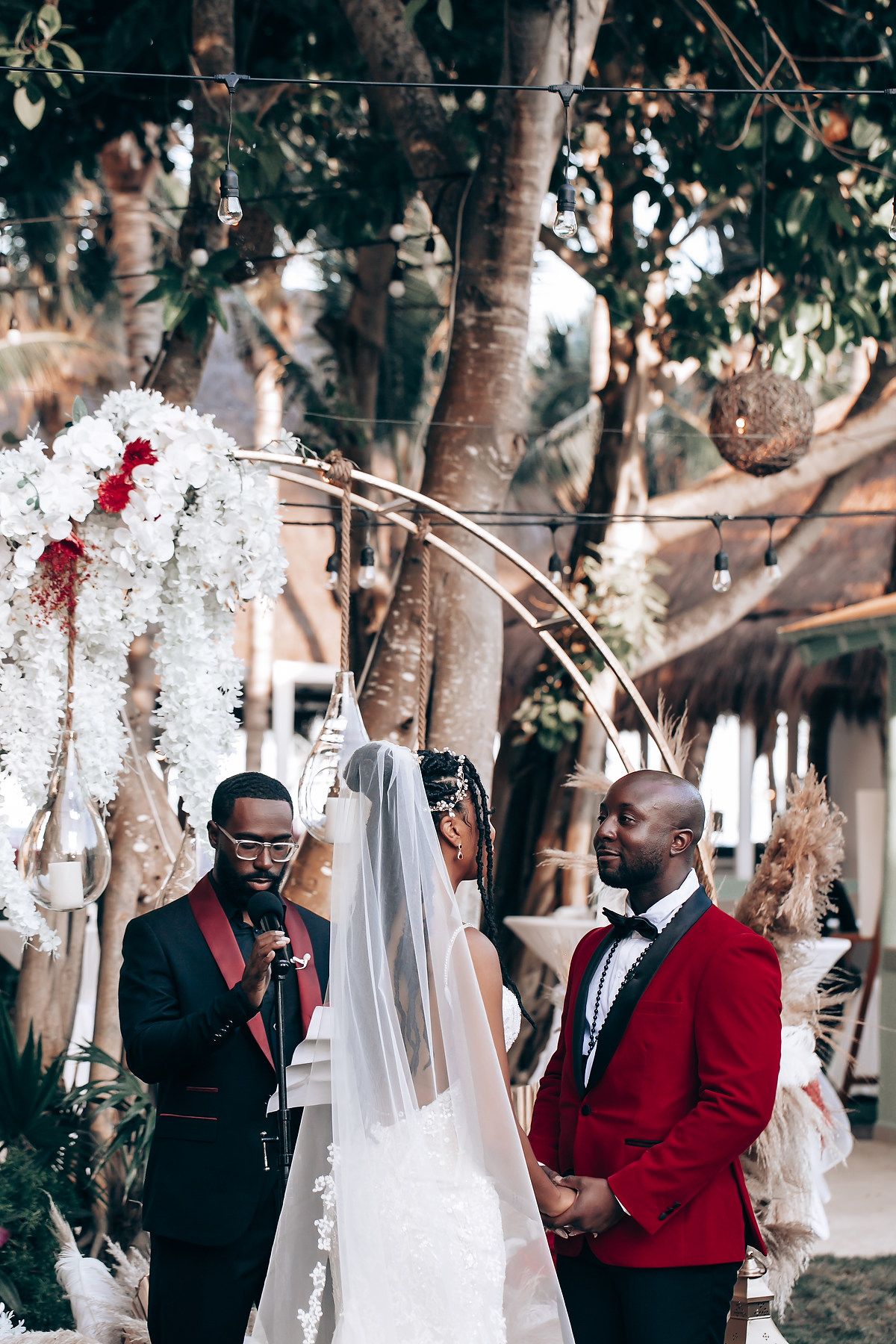 Wedding couple shares intimate moments in a garden setting with red and black color theme.