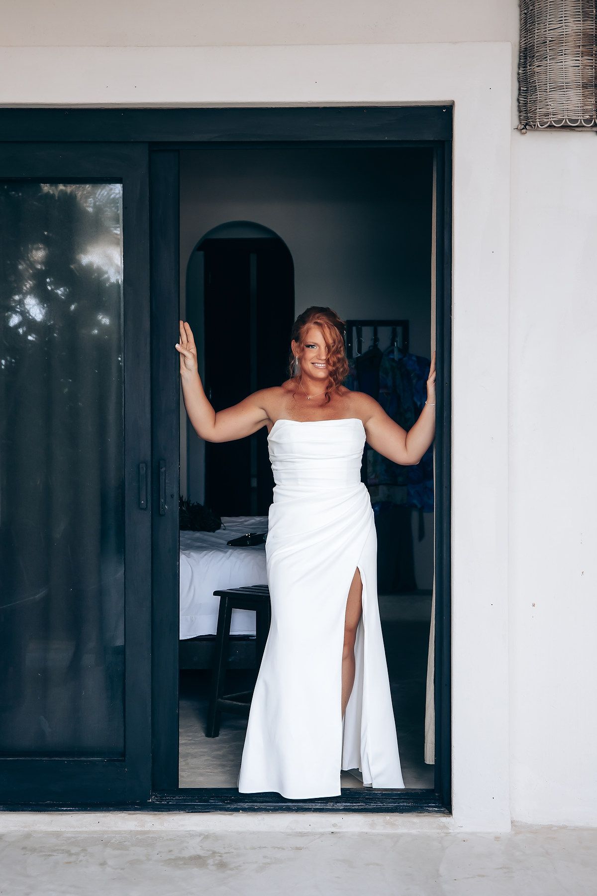 White-clad figure posing in doorways of modern tropical building.