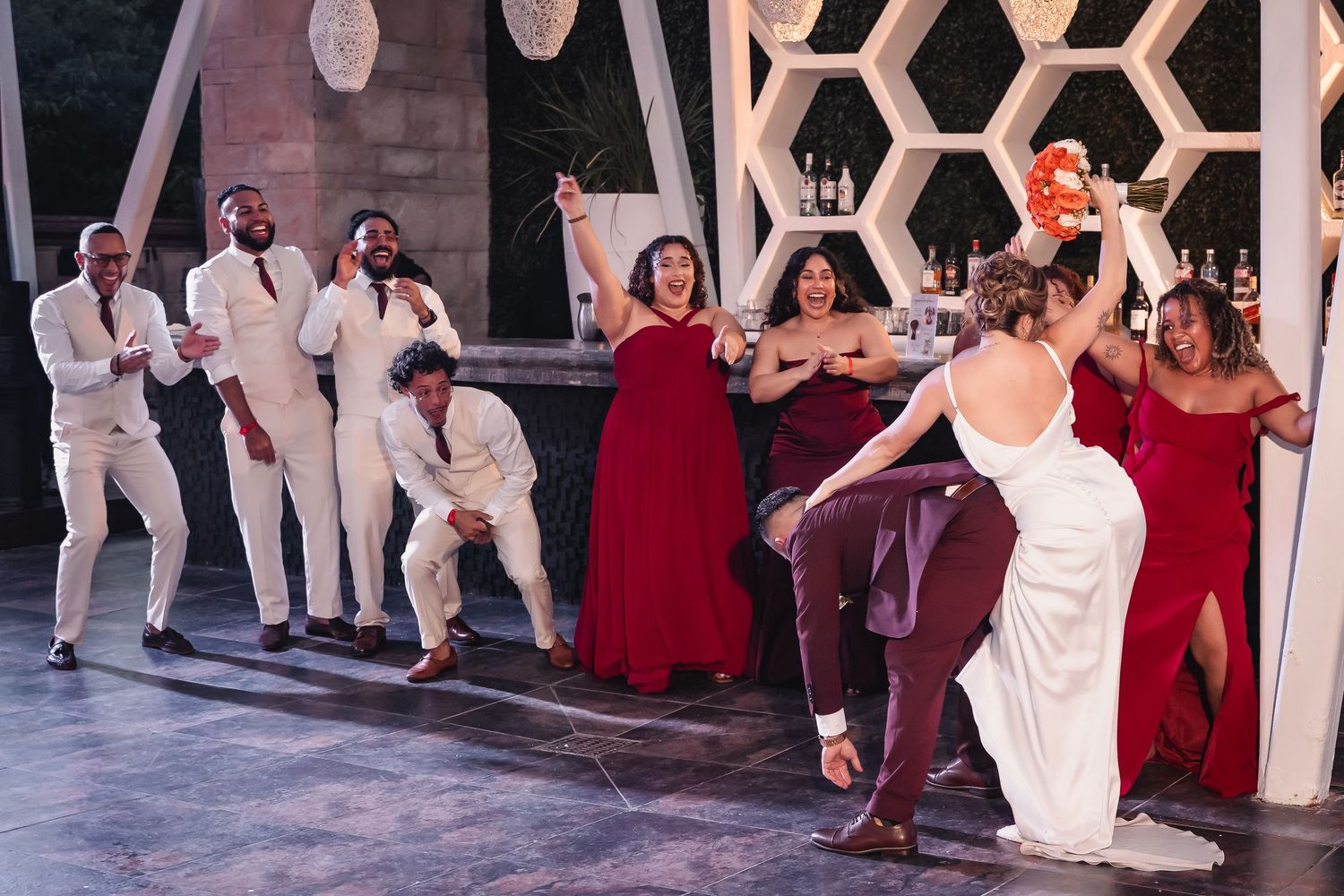 Wedding reception dance floor with geometric honeycomb pattern backdrop and burgundy decor.