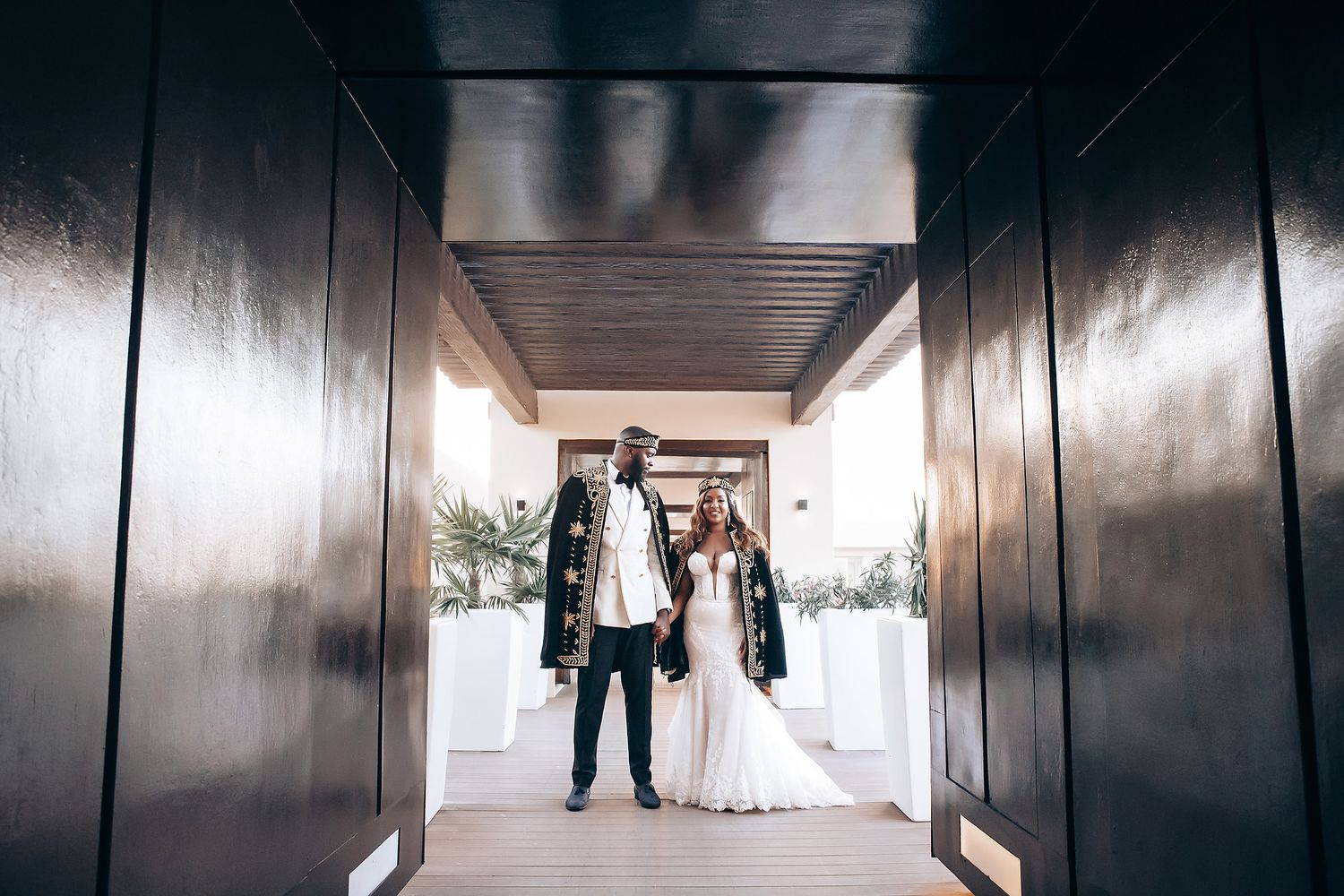 Wedding party walking through a modern hallway with dark walls and dramatic lighting.