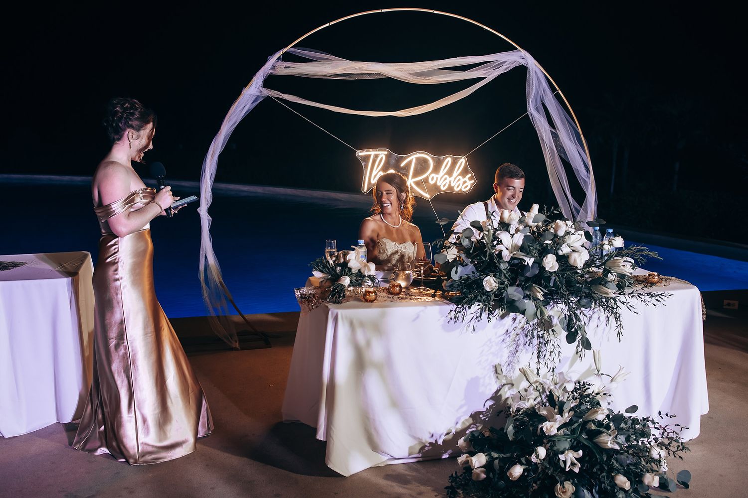 Wedding reception tables decorated with white linens and floral centerpieces in an elegant venue.