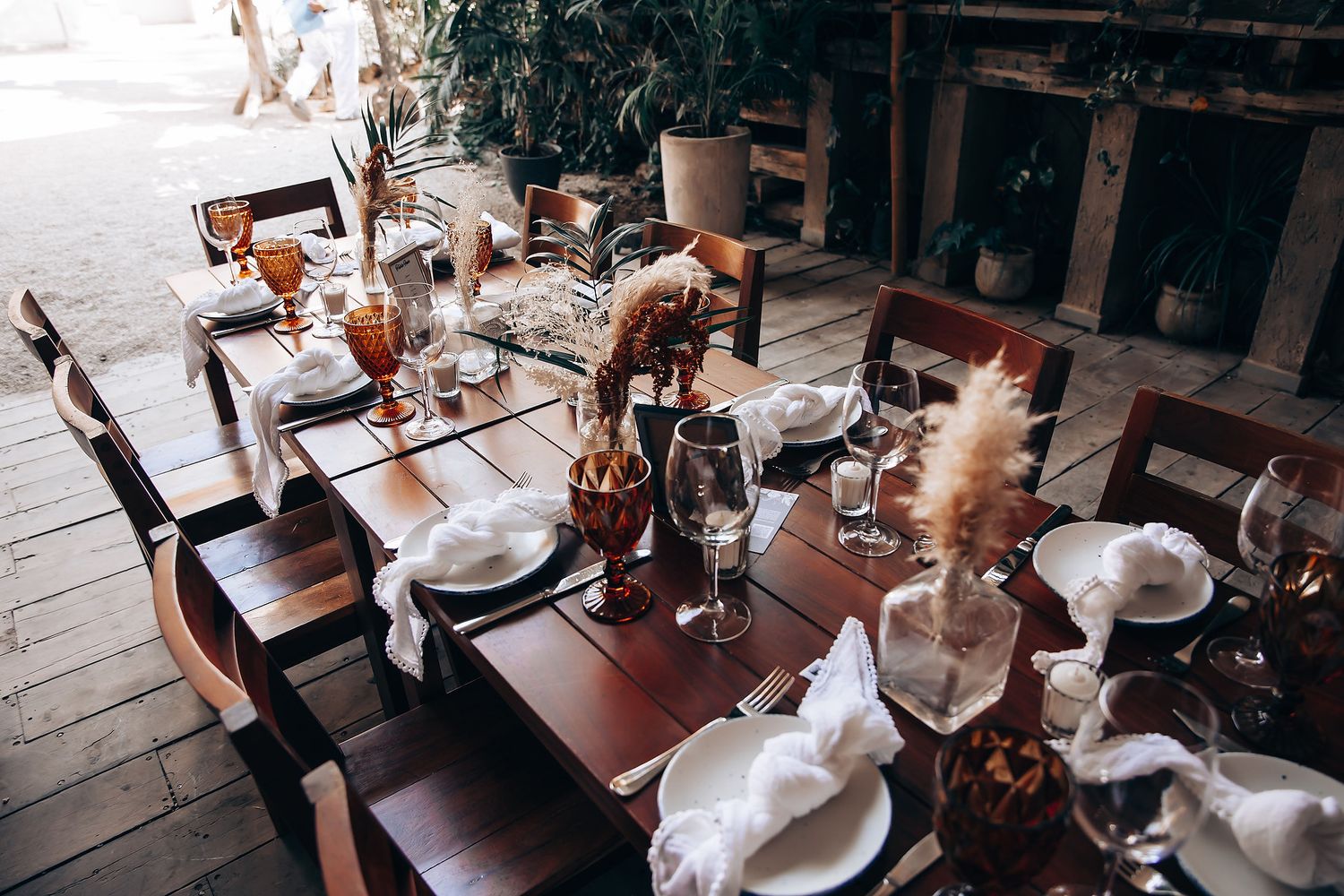 Elegant table settings with glassware and candles arranged for a formal dining event in a rustic wooden space.