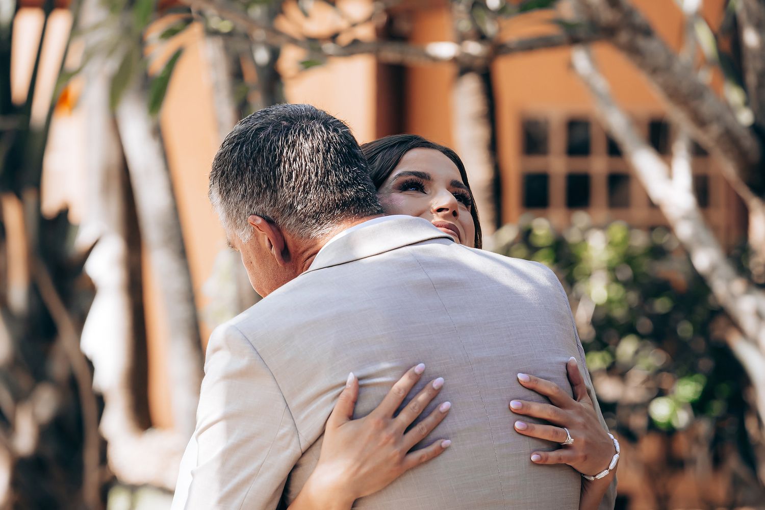 Wedding guests embrace and congratulate each other during an outdoor celebration at sunset.