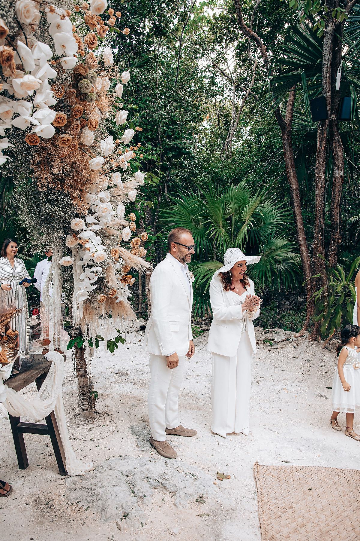 Elegant outdoor wedding ceremony setup with neutral balloon arch decorations and tropical foliage in a natural setting.