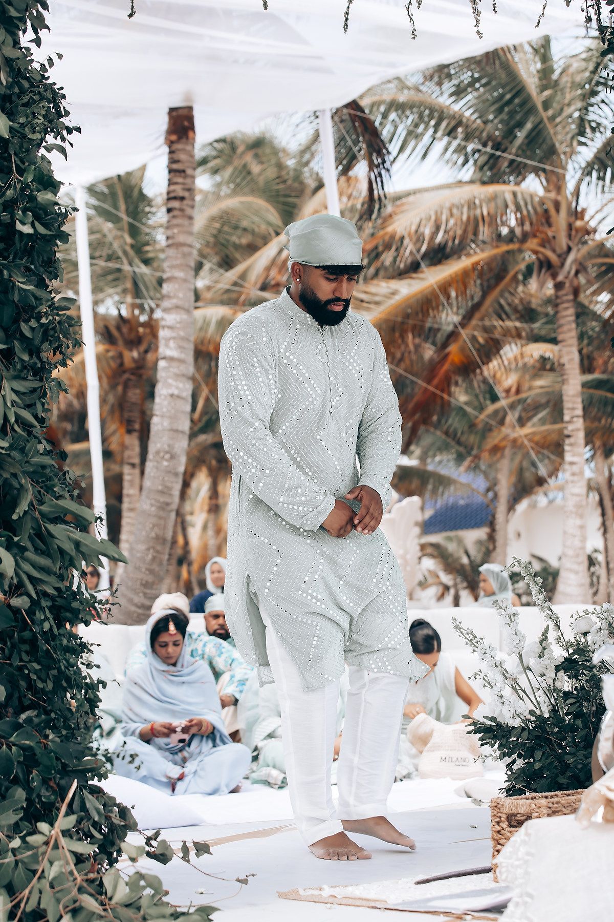 Traditional Indian wedding ceremony setup with white decor among tropical palms.