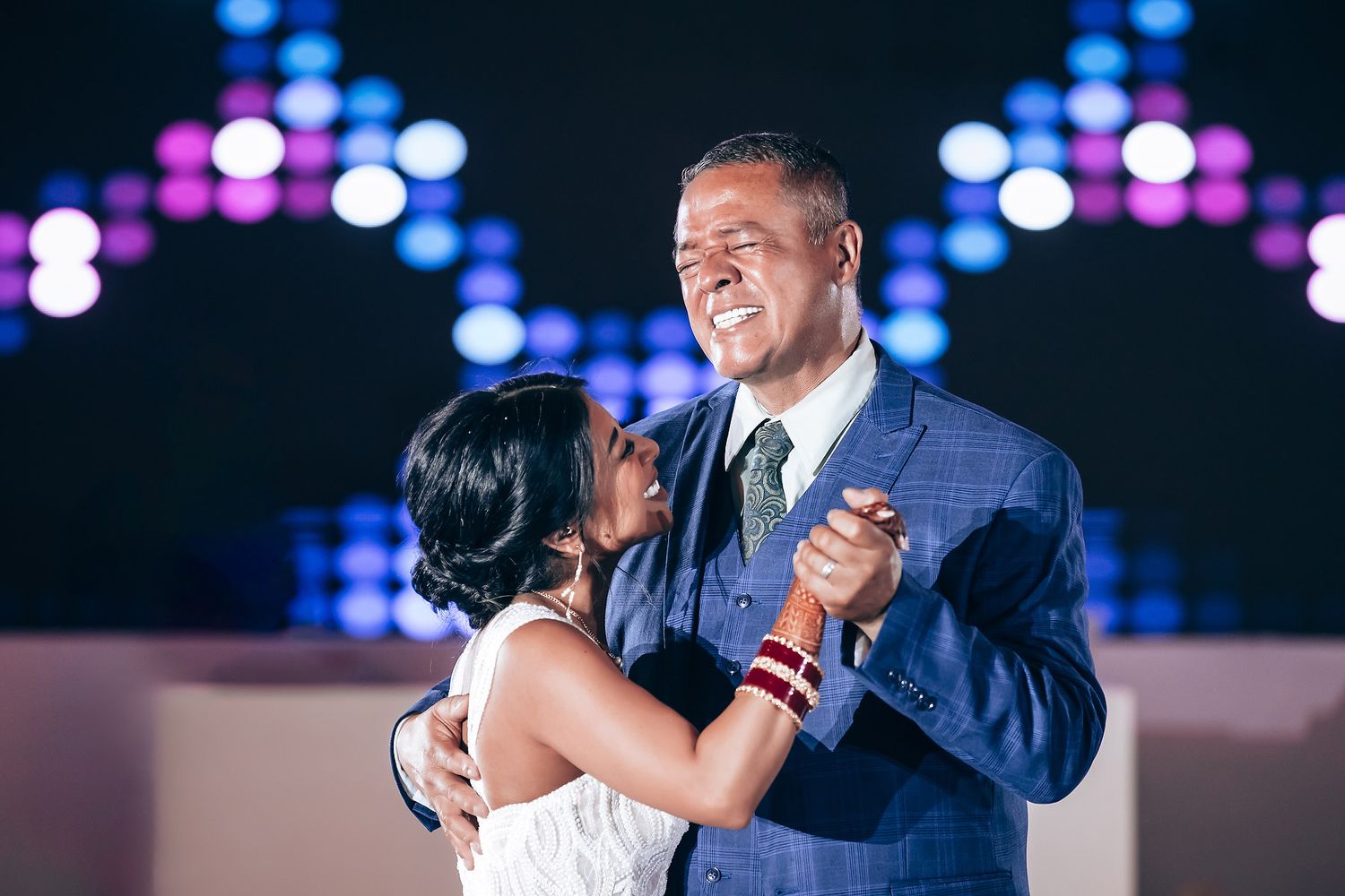 Joyful dance moment captured at a wedding reception with blue lighting effects.