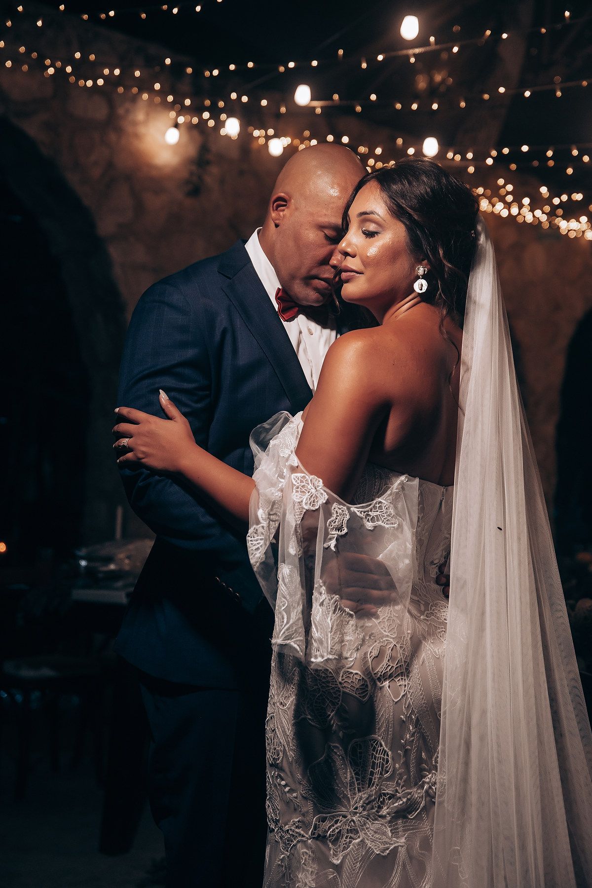 Intimate wedding portrait under twinkling lights creating a romantic evening atmosphere.