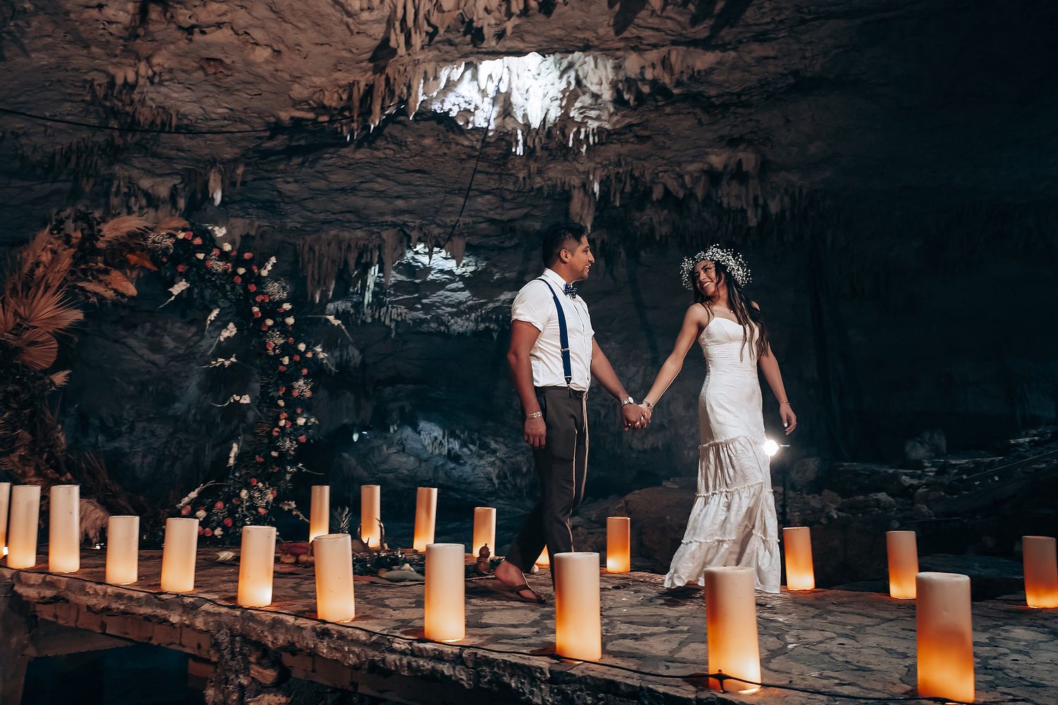 Illuminated pathway in a natural cave decorated with paper lanterns creating an ethereal wedding atmosphere.