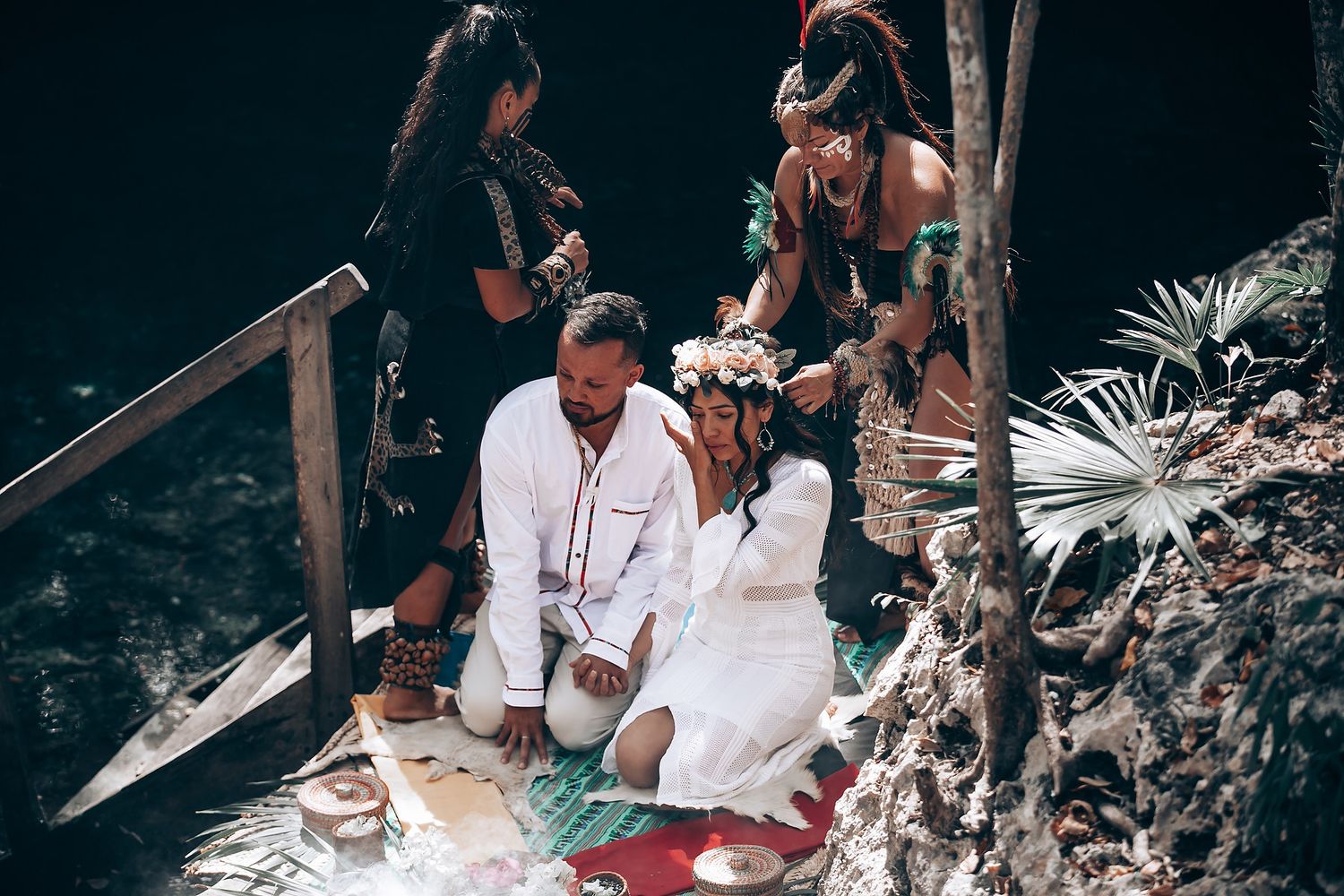 People gather in a wooded area for a spiritual ceremony with smoke and ritual elements in natural surroundings.