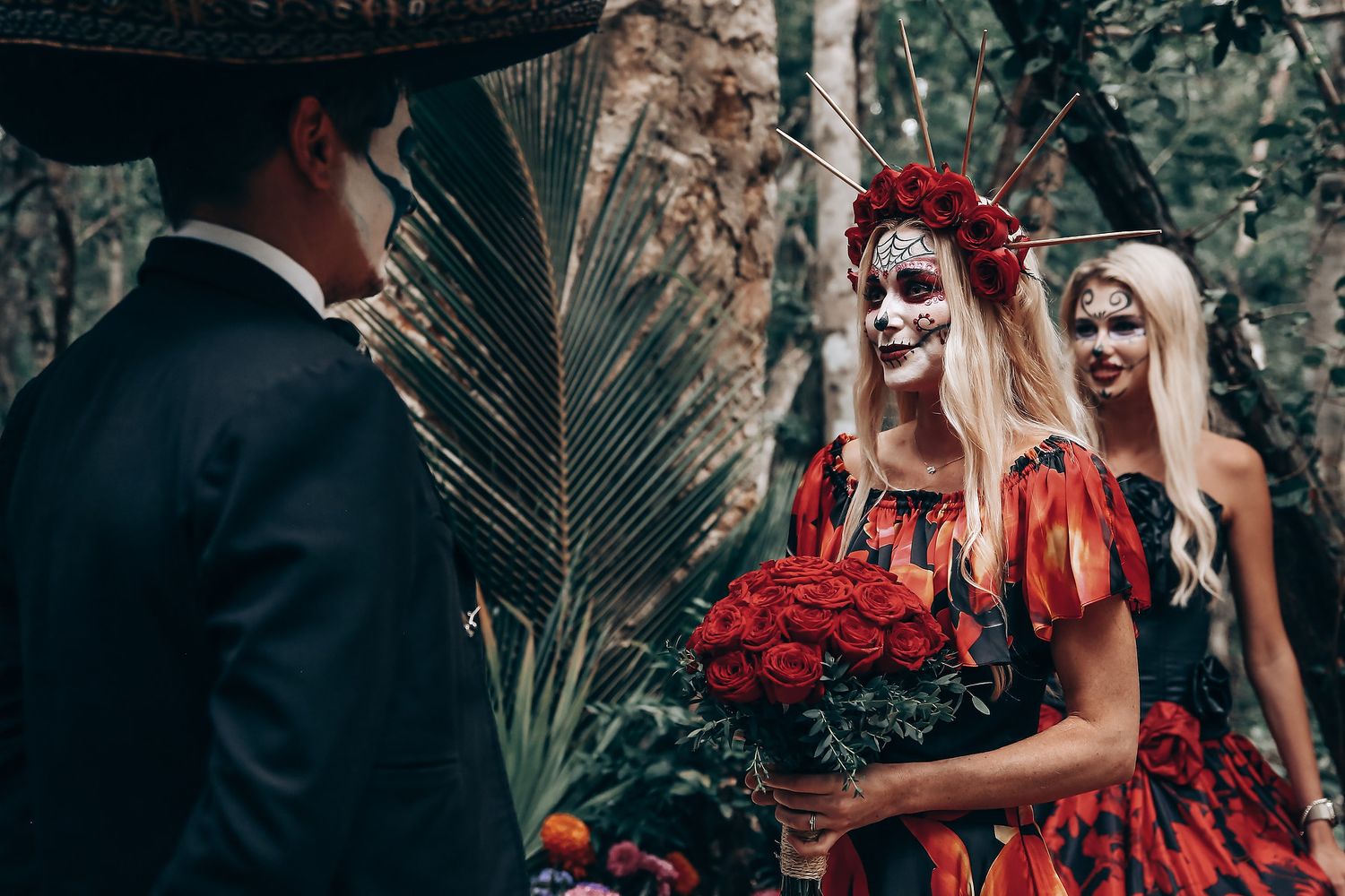 Gothic wedding scene with red roses and black attire in a moody forest setting.