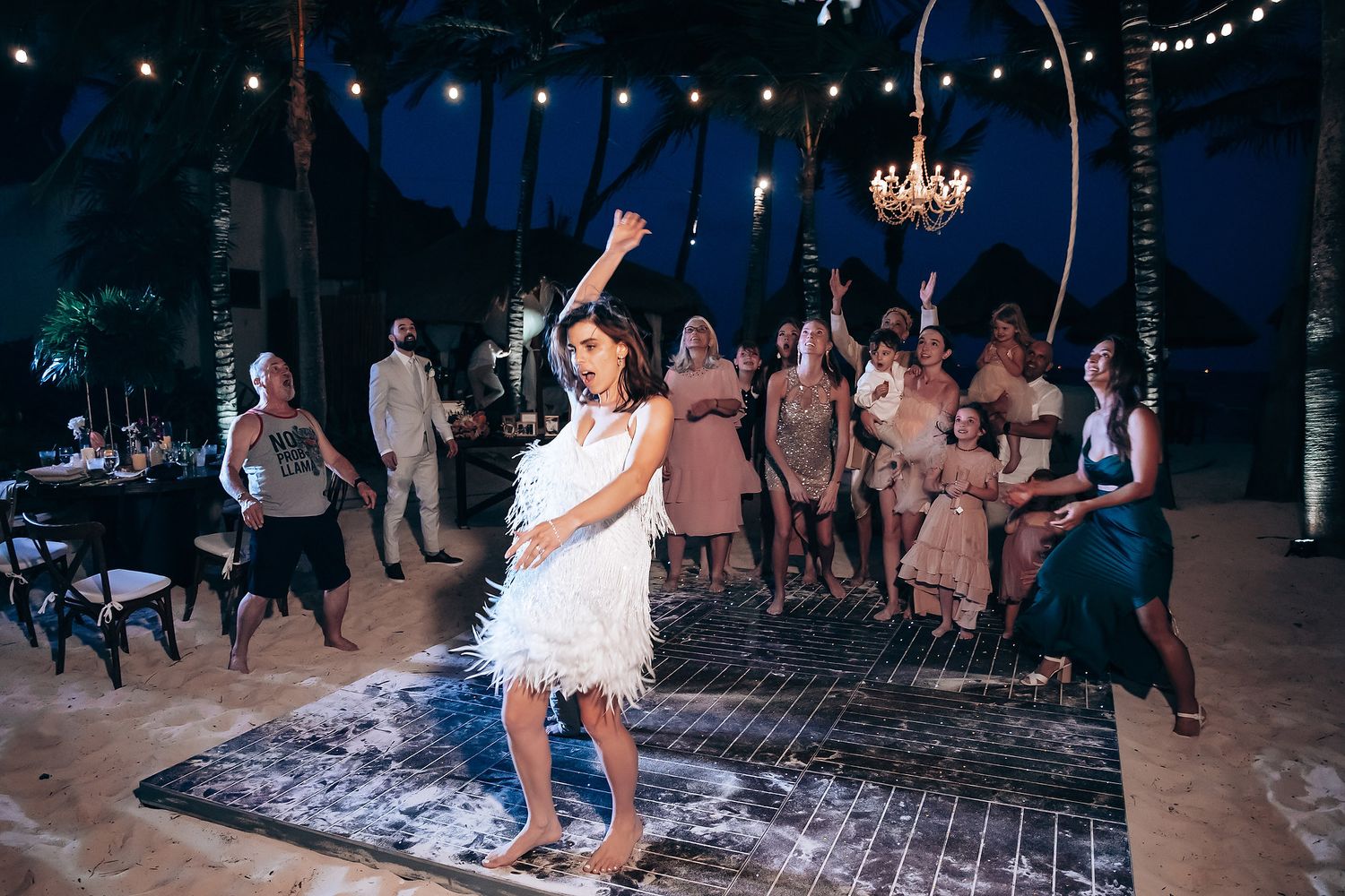 Evening wedding reception with string lights and chandeliers creating a magical dance floor atmosphere.