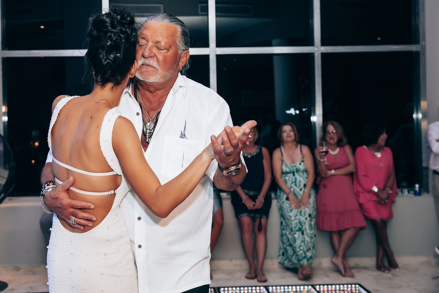 Wedding reception dance floor moments with guests celebrating in background.