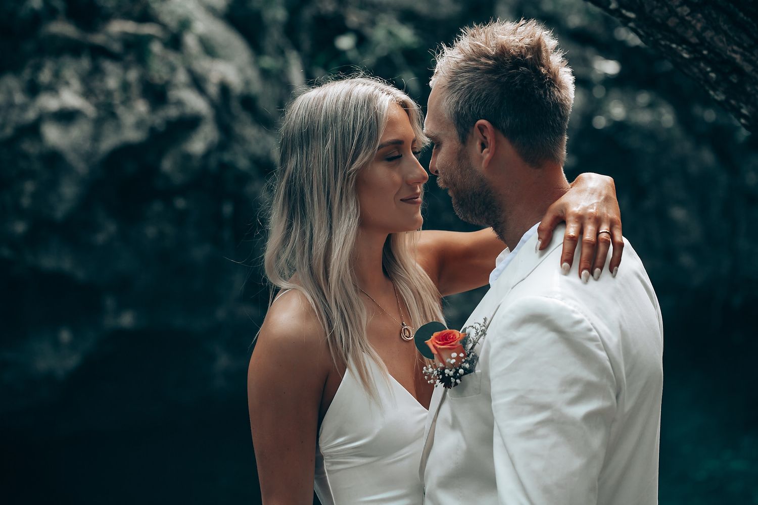 Newlyweds share a romantic moment on a wooden platform inside a scenic cave setting.