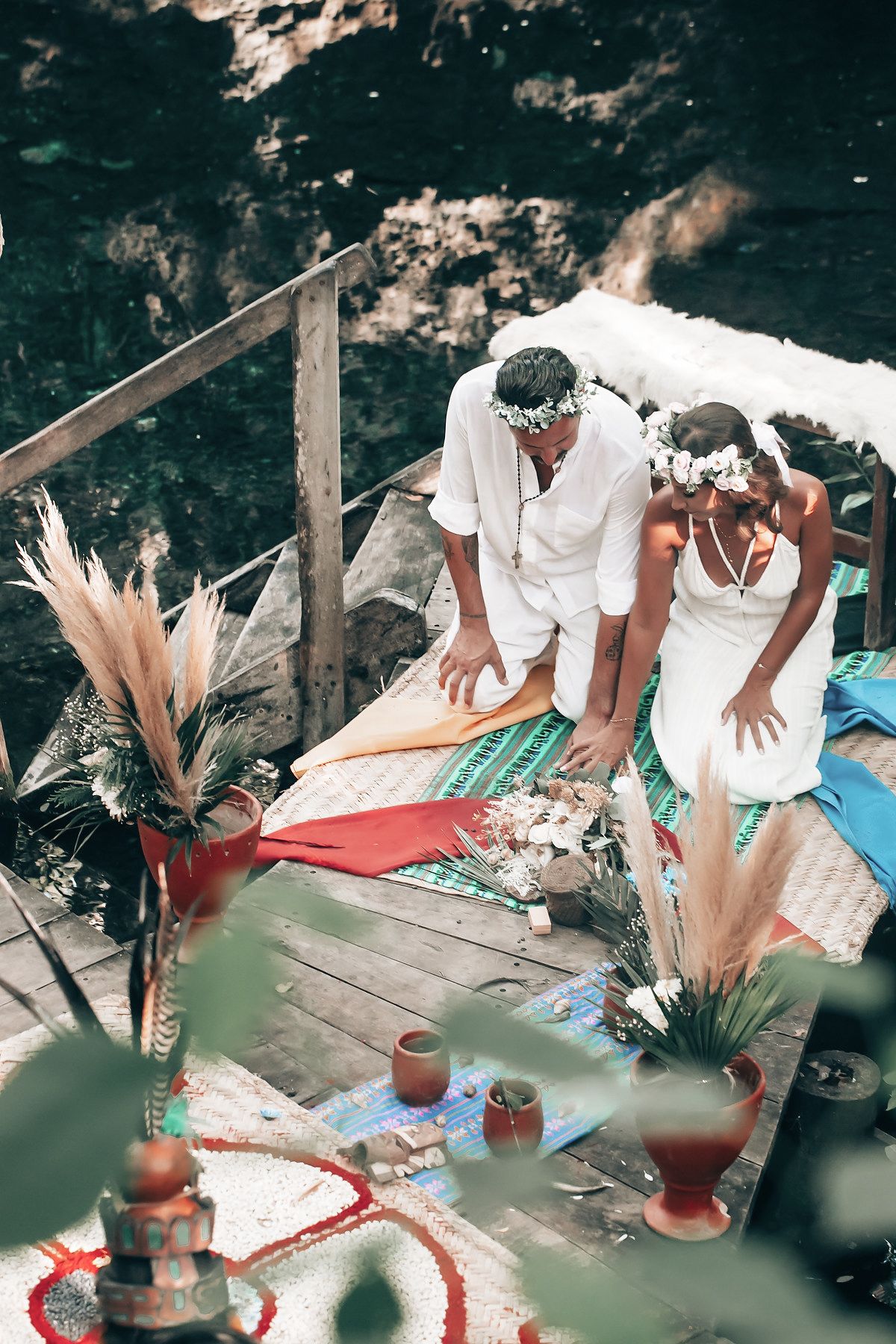 A person in traditional attire performs a ritual or ceremony in a lush, tropical environment.