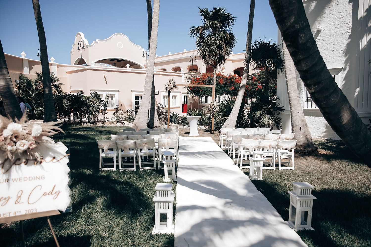 An outdoor wedding ceremony set up with white chairs and decorations.
