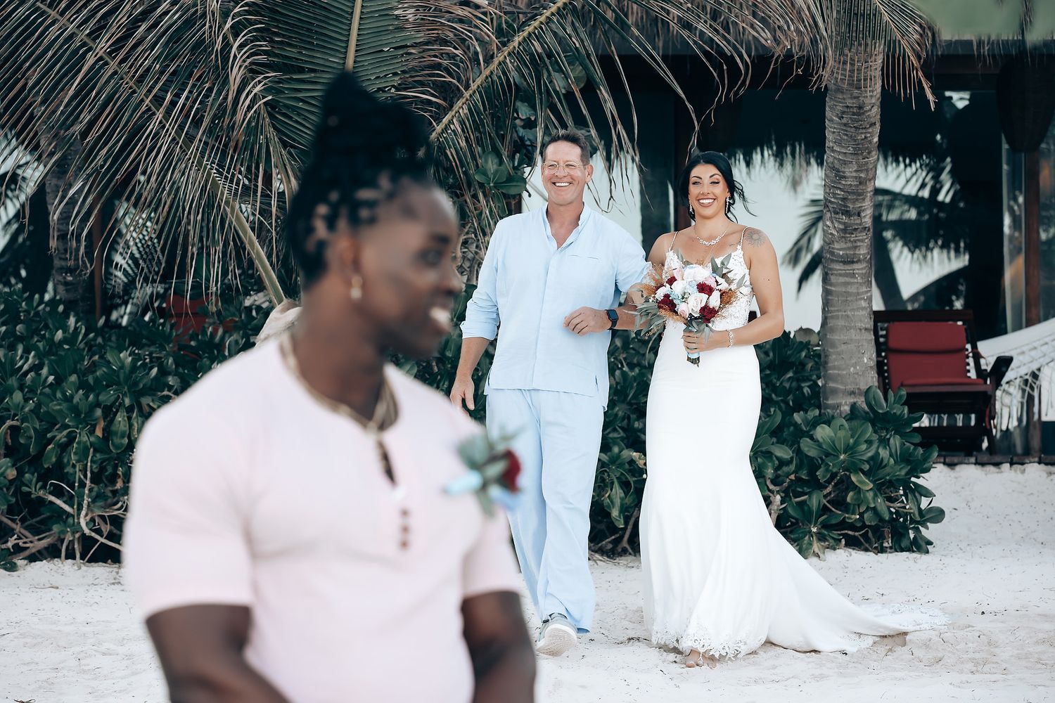 A wedding ceremony taking place on a beach with a couple and their guests.