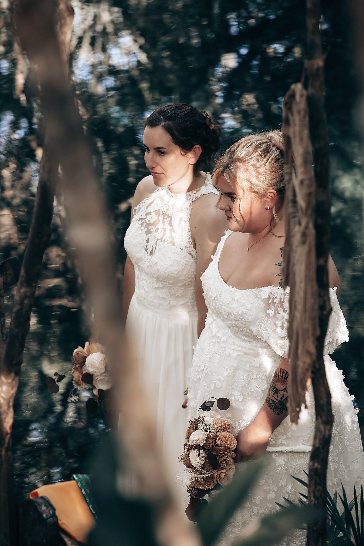 The image shows a bride and groom standing in a lush, forested setting, with the bride holding a bouquet of flowers.