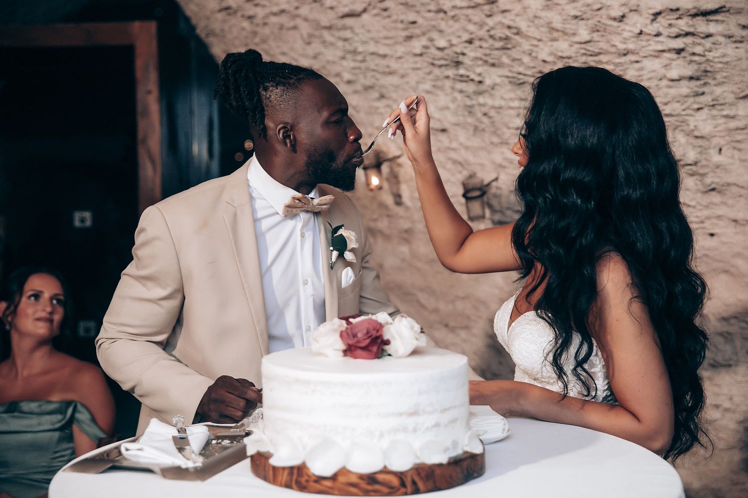 A wedding cake cutting moment captured during an intimate outdoor reception celebration.