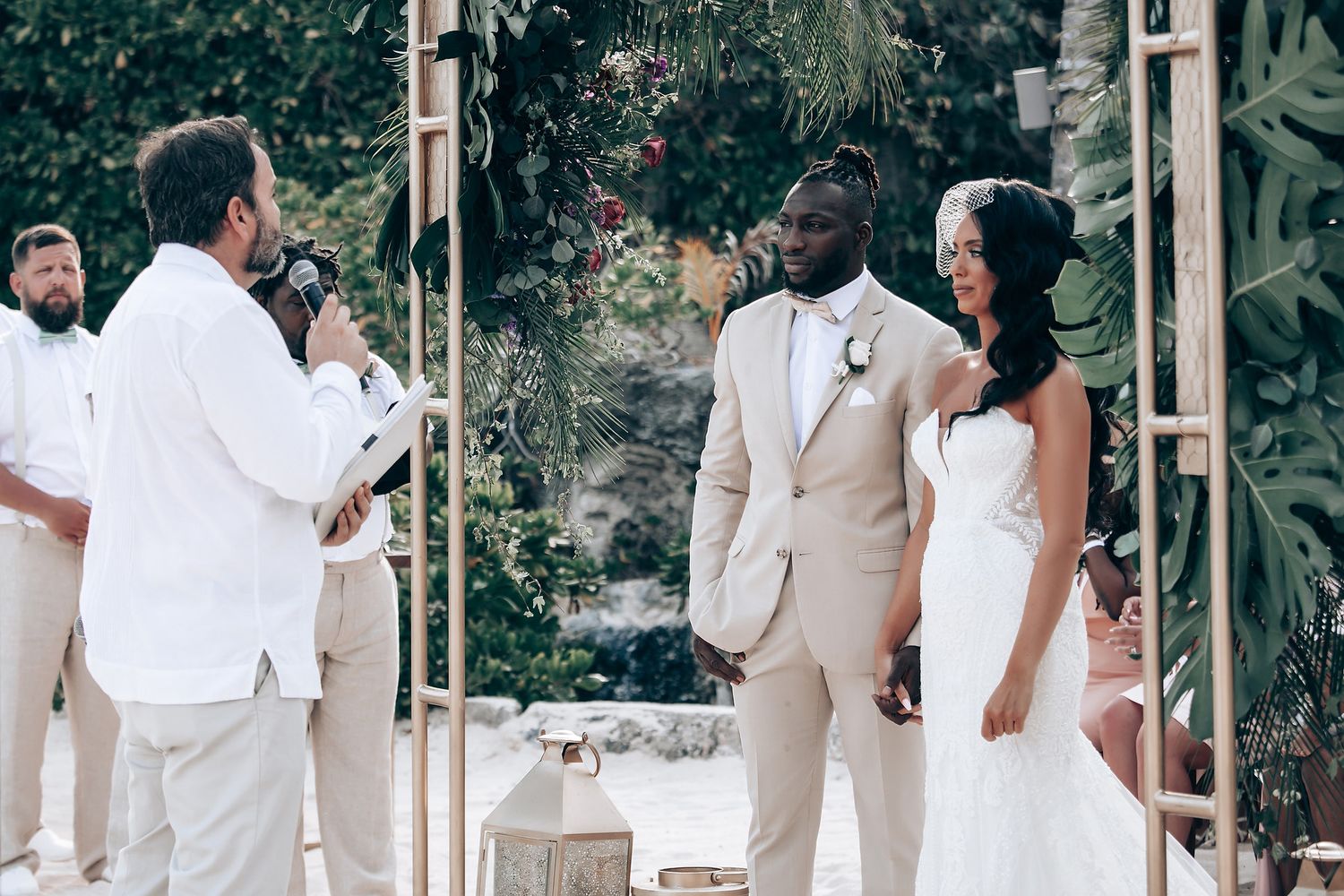 A wedding ceremony setup outdoors with white chairs and floral arrangements under a wooden pergola.