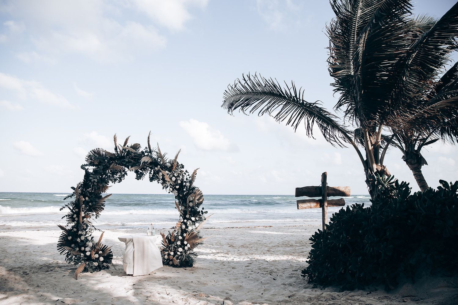 Tropical beach wedding setup with palm trees swaying in the wind.