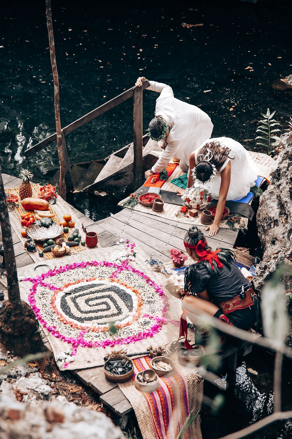 Overhead view of a spiral floral pattern on wooden platforms during forest wedding ceremony.