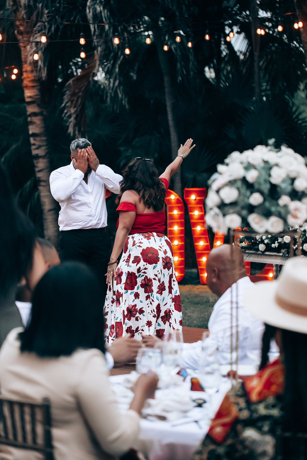 Evening wedding reception with red lanterns and floral decorations.