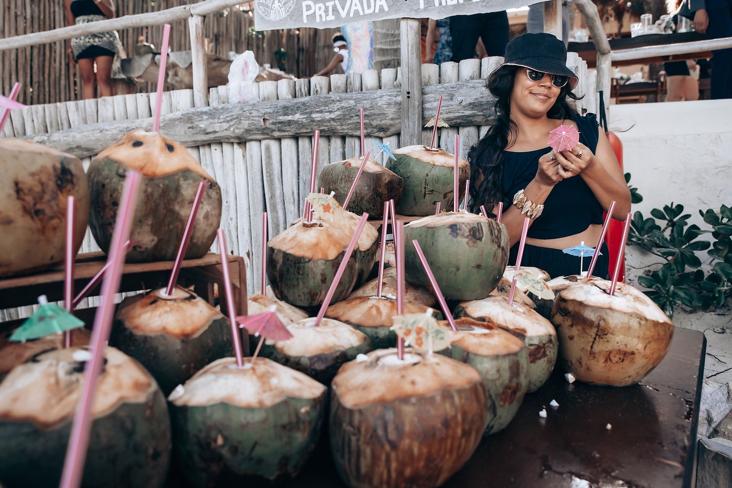 Coconuts with straws arranged as tropical drinks at a beach bar event.