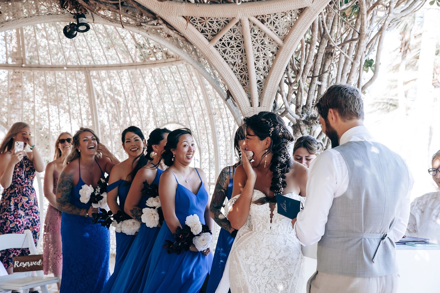 Wedding ceremony guests seated beneath an ornate white canopy structure.