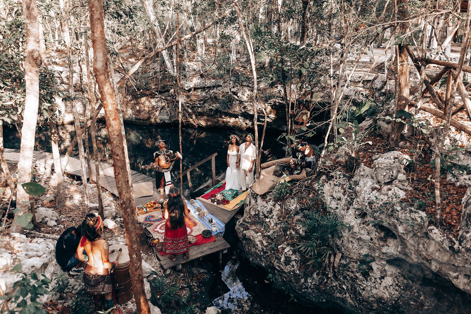 An aerial view of a cenote ceremony space with natural rock formations and trees.