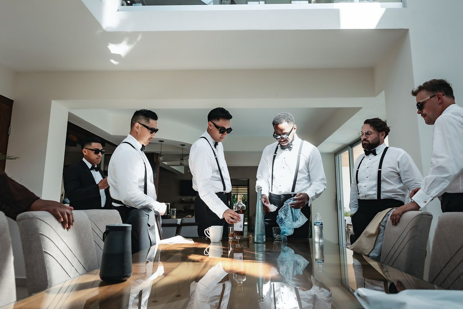 Groomsmen in white shirts and suspenders preparing together before a wedding ceremony.