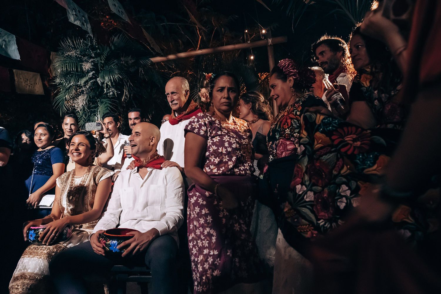 Wedding guests seated and watching the celebration in an outdoor tropical venue.