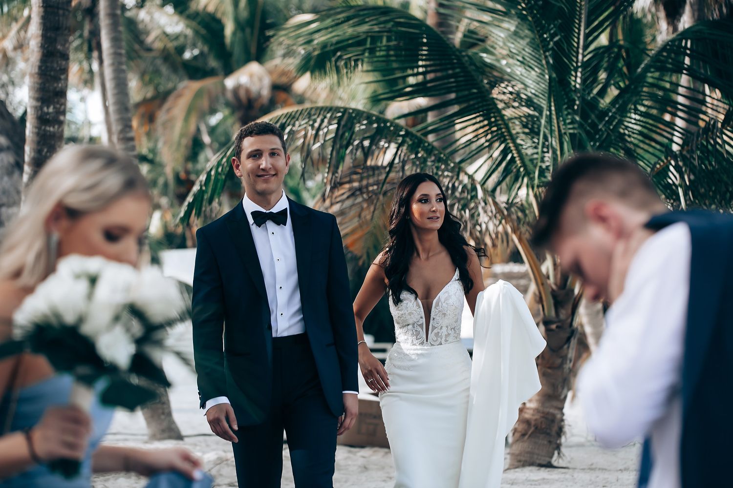 A tropical beach wedding ceremony with palm trees and formal attire.