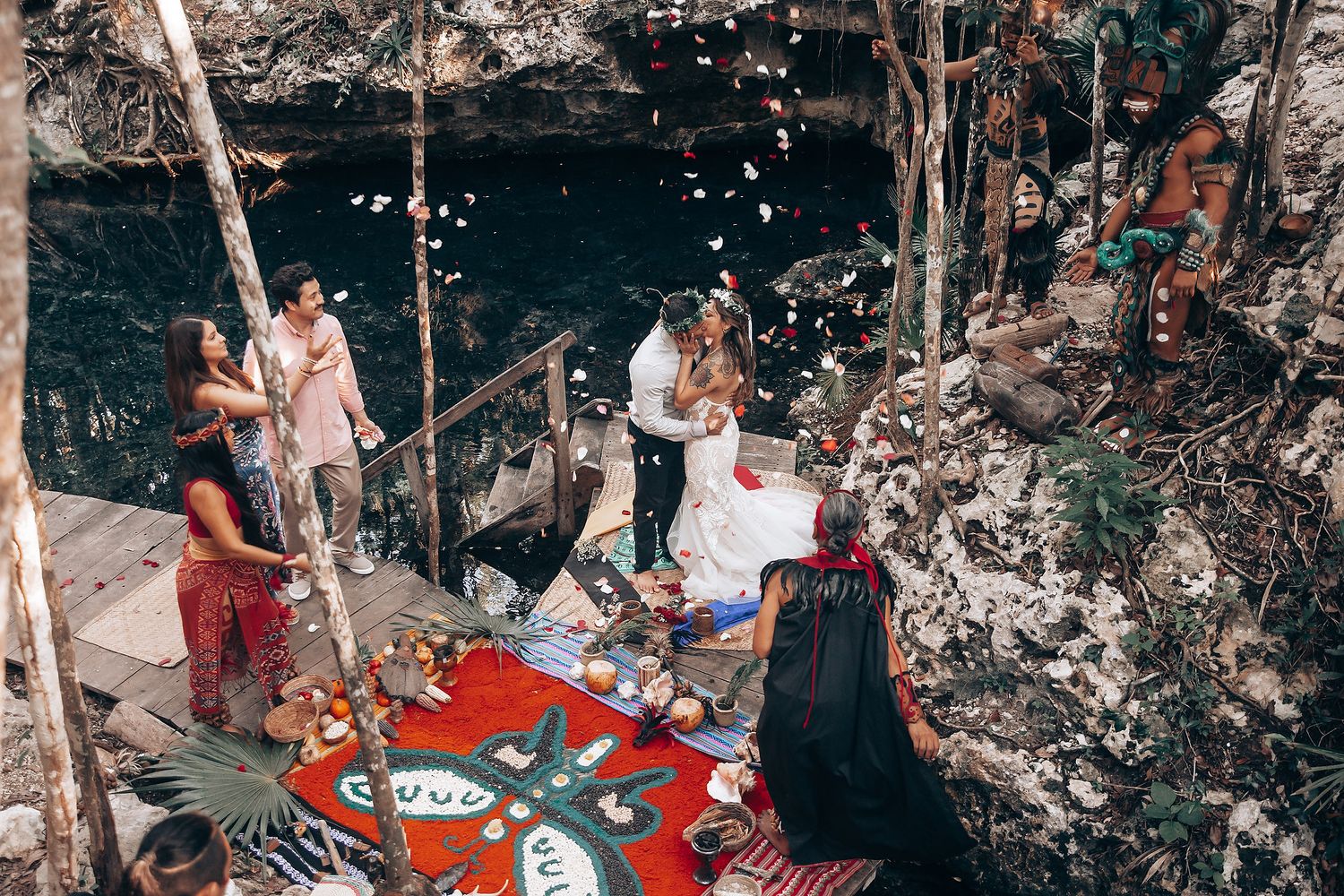 Outdoor wedding celebration in a cave setting with red blanket and decorative elements.