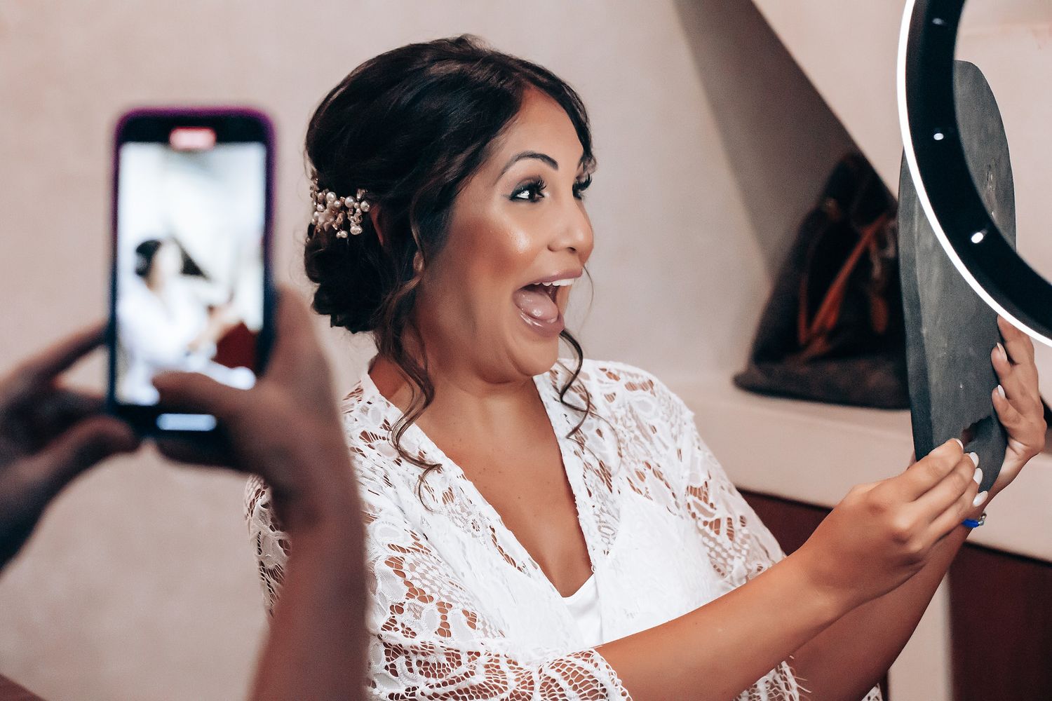 Person wearing elegant white lace dress while getting ready in a brightly lit room.