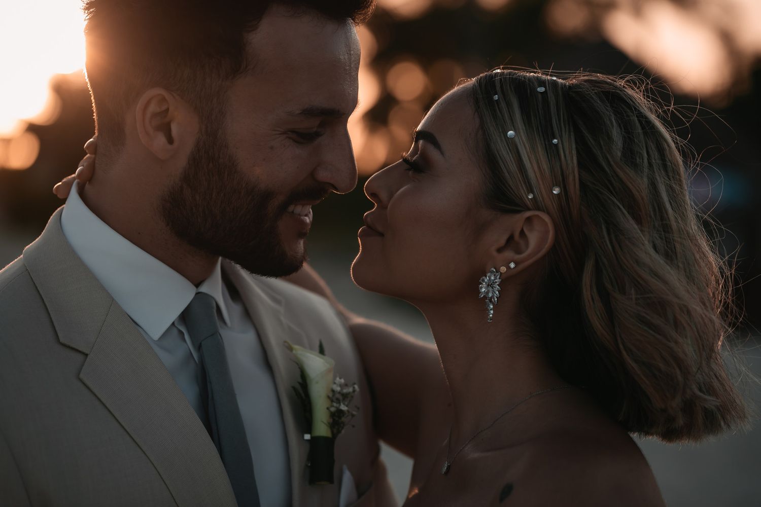 Intimate golden hour portrait of smiling bride and groom gazing at each other at sunset.