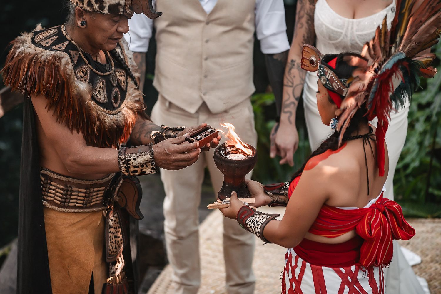 Mayan shaman performing traditional wedding ceremony ritual with couple, offering sacred elements in tropical setting.