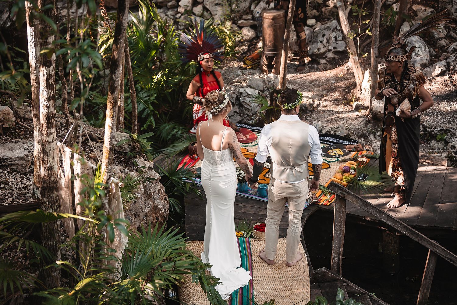 Couple exchanges vows in lush jungle ceremony with colorful officiant and tropical altar decorations.