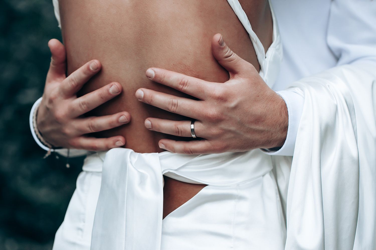 Intimate close-up photograph showing gentle embrace in white fabric.