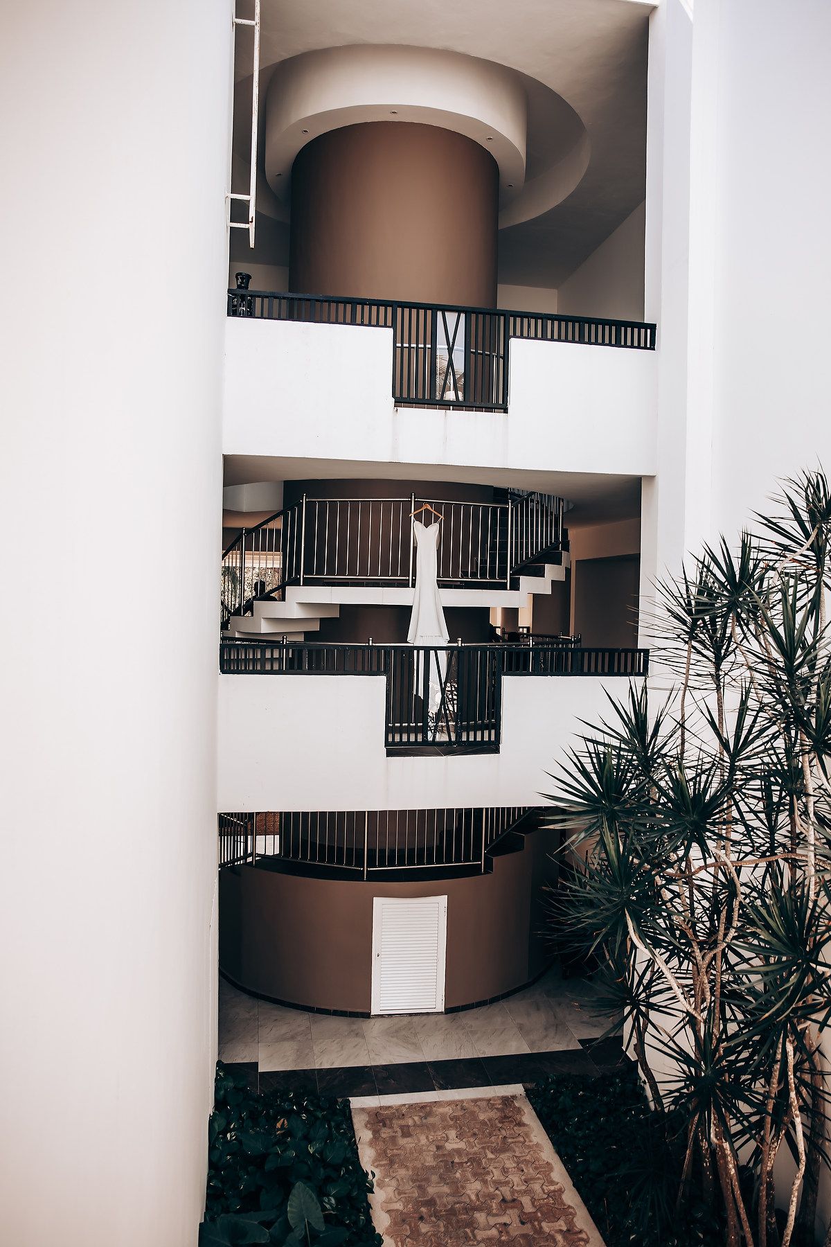 Modern architectural interior with curved balconies and white columns creating geometric patterns in a hotel or apartment building.