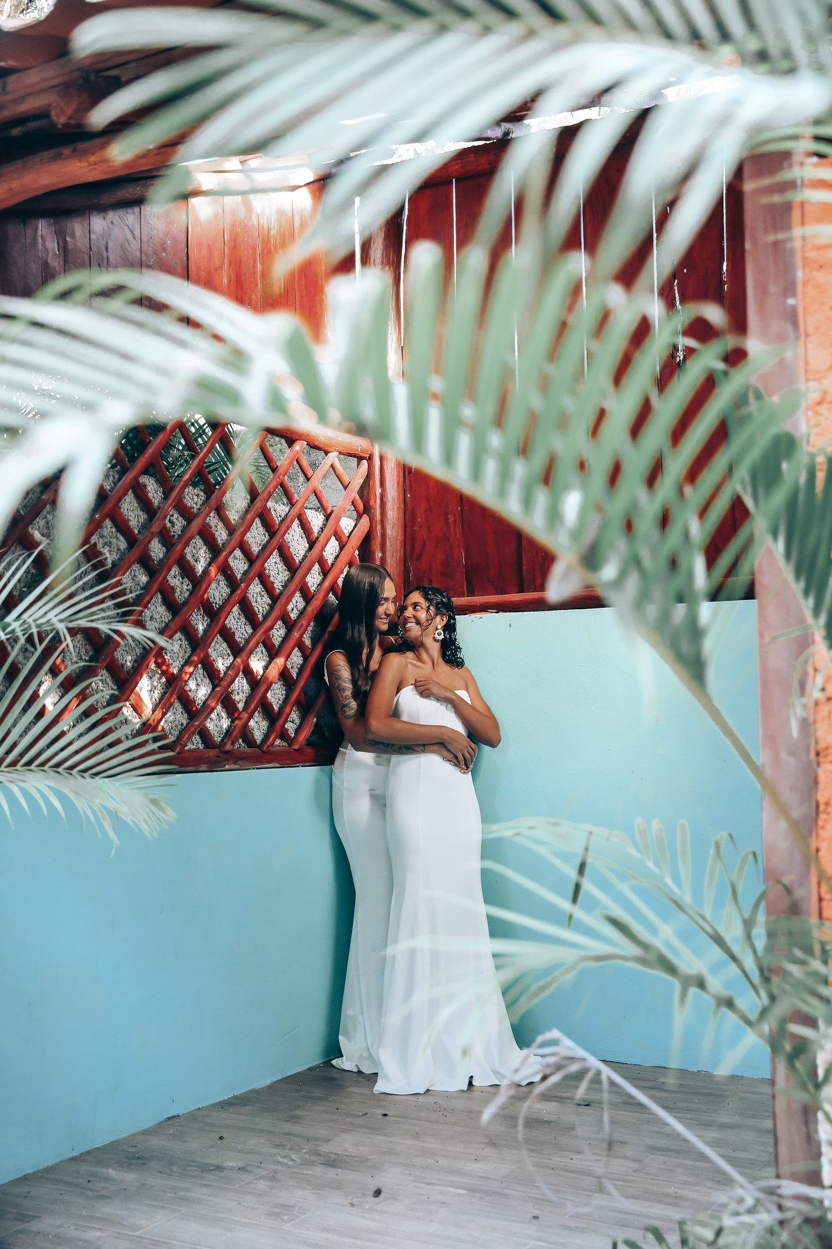 Tropical wedding setting with palm fronds and turquoise walls in an open-air venue.
