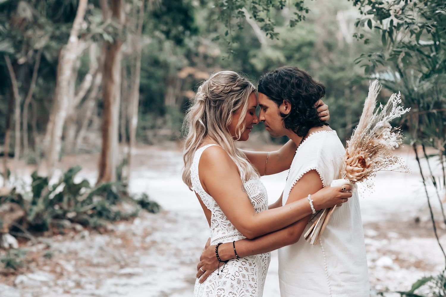 A romantic couple embraces in a dreamy outdoor setting with soft natural lighting and lush greenery.
