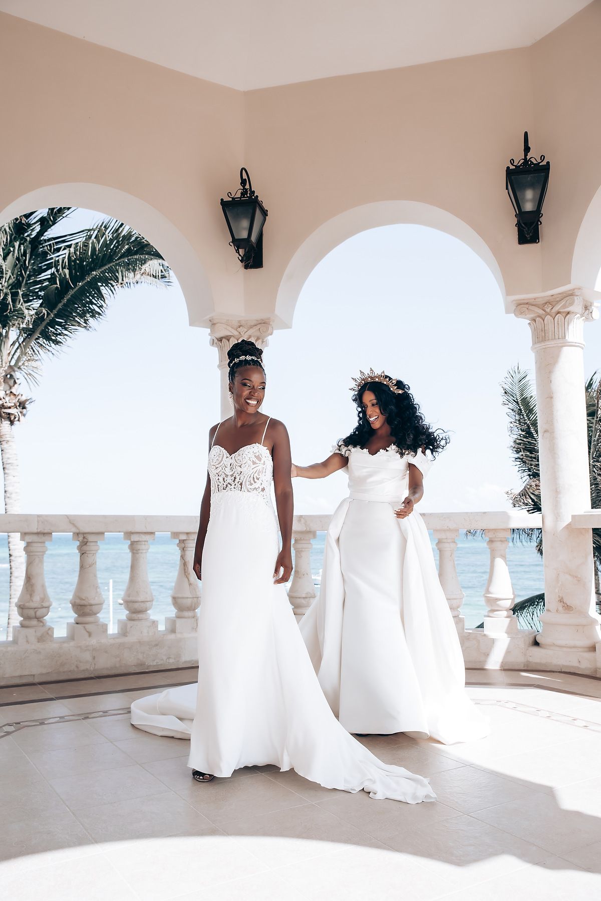 White columned terrace overlooking ocean with arched architecture and tropical palm trees.