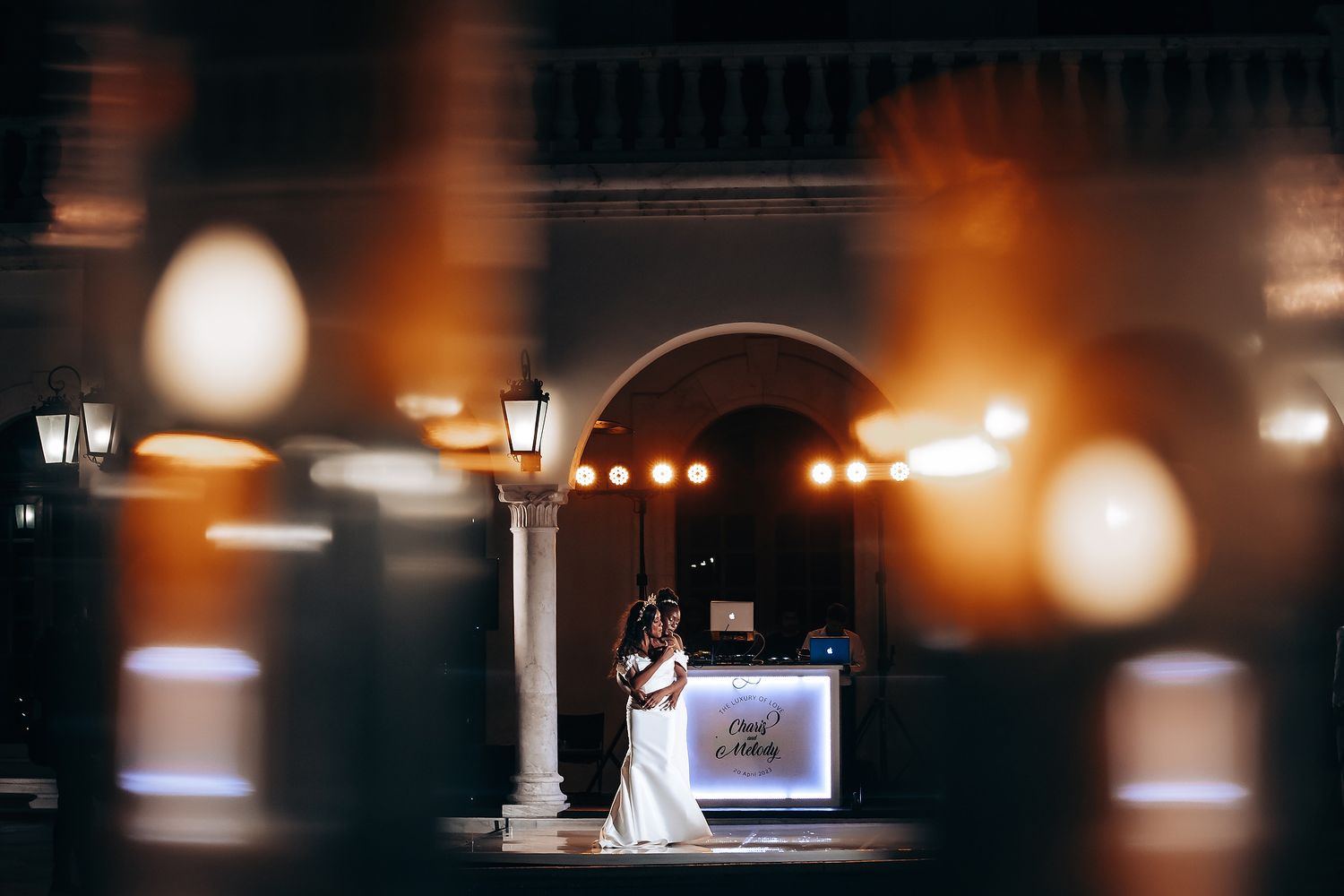 A romantic nighttime wedding scene with glowing lights and architectural columns.