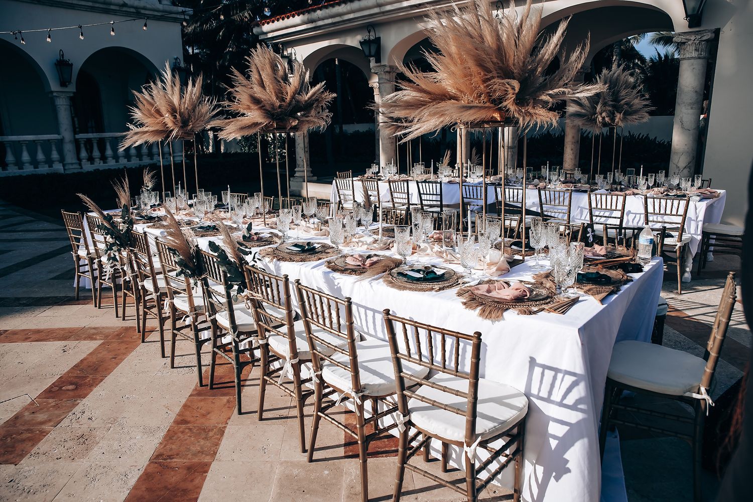 Elegant wedding reception setup with white chairs and table settings under an outdoor pavilion.