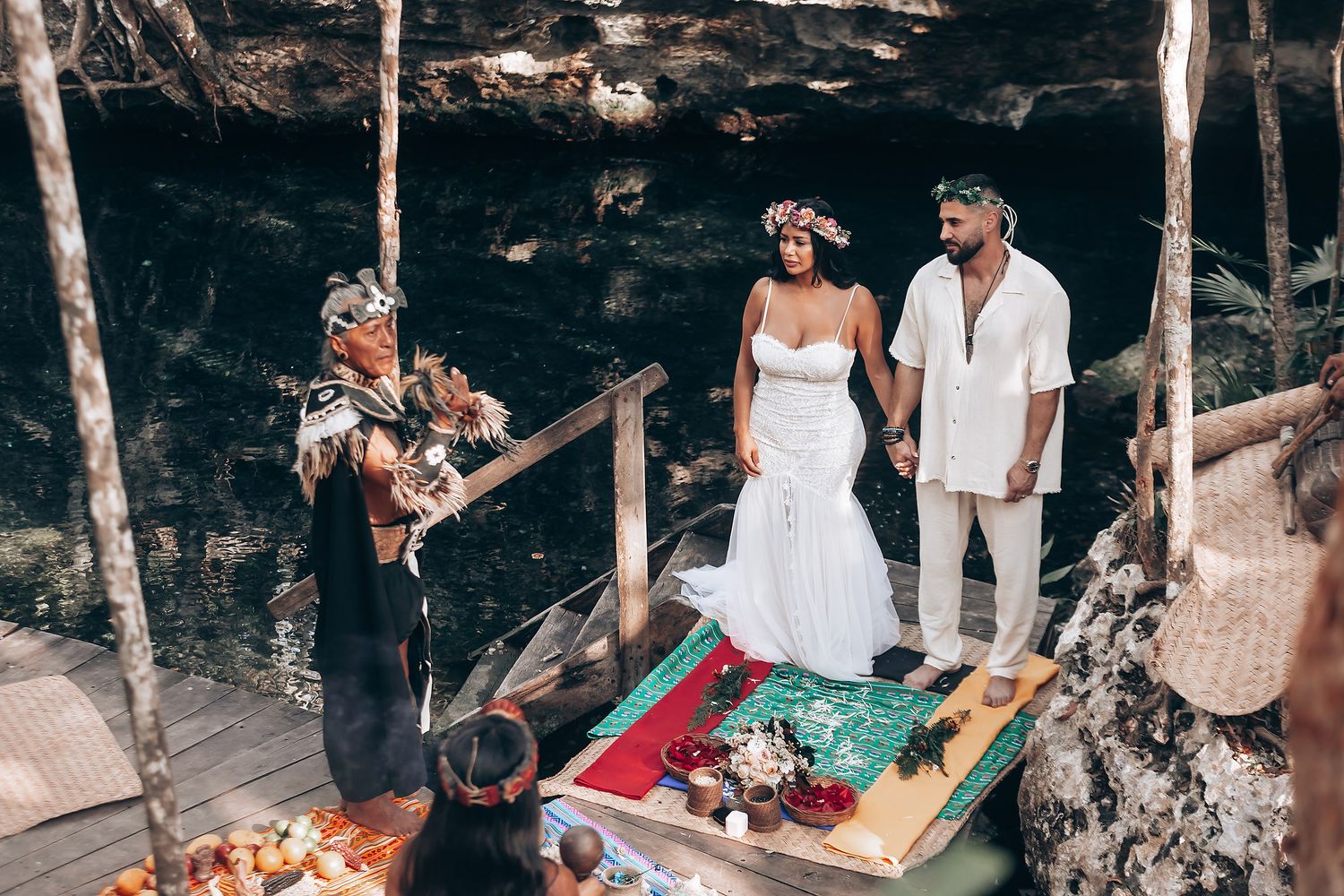 Wedding guests gathered at a natural cenote location surrounded by trees and wooden platforms.